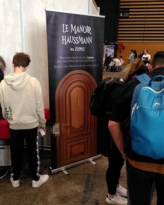 La porte du Manoir Haussmann, un roll-up devant lequel les joueurs se pressent.