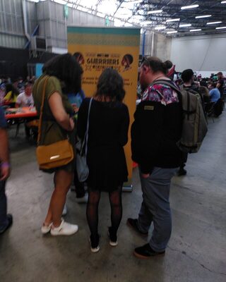 Des joueurs, de dos, devant un roll-up du jeu.