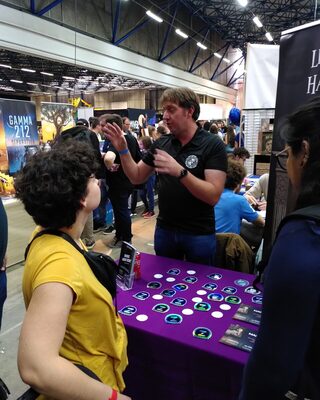 L’animateur explique le jeu à une joueuse, devant le roll-up du manoir.