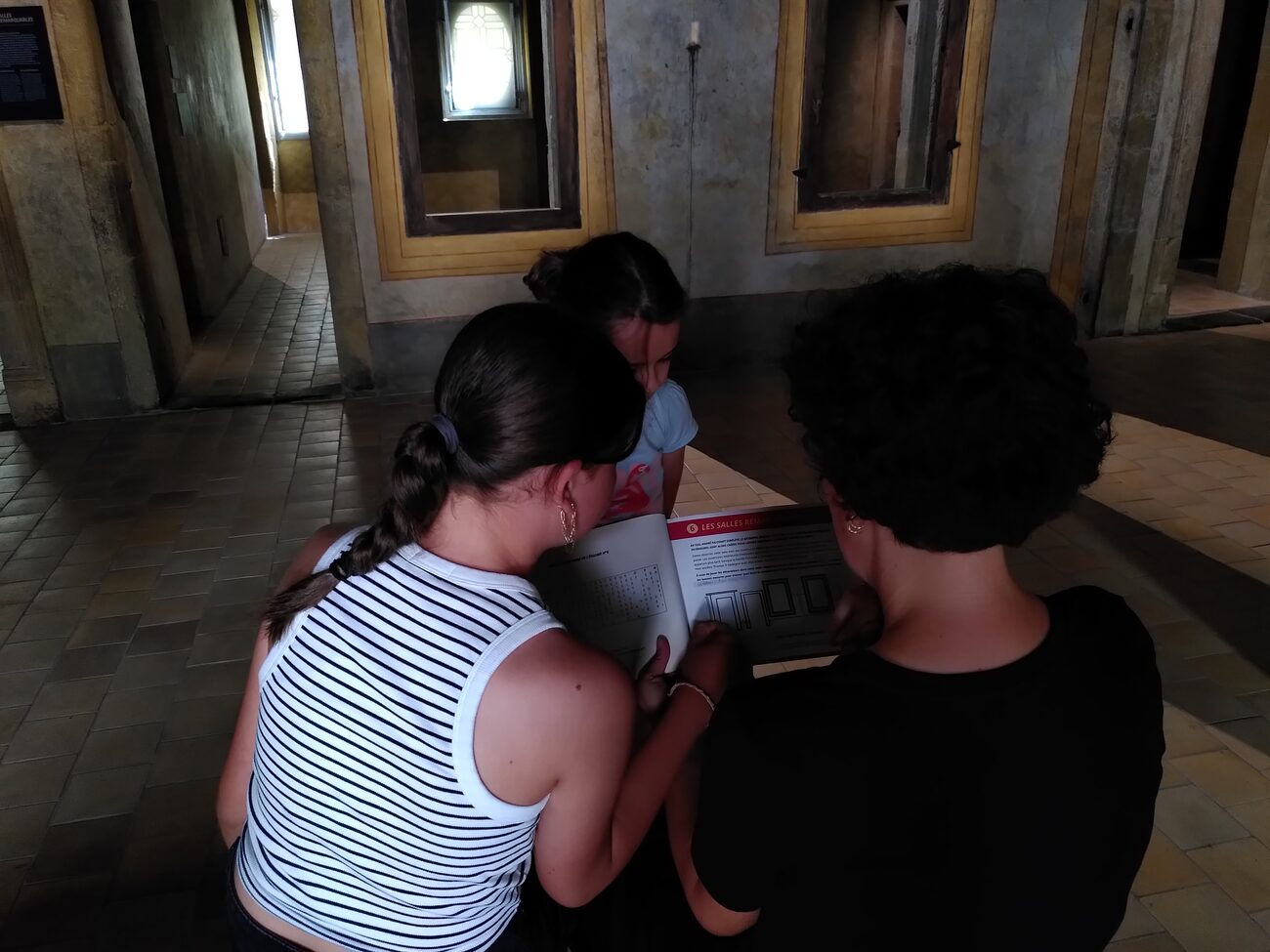 Bêta-test dans le musée&nbsp;: des visiteurs résolvent les énigmes du carnet, vus de dos
