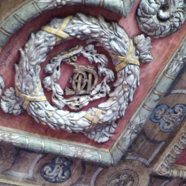 Détail du plafond peint et sculpté, avec un blason dans une couronne de laurier